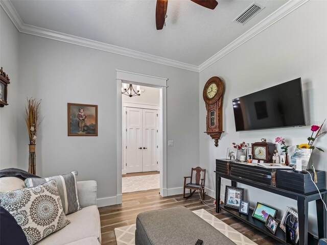 living room featuring hardwood / wood-style flooring, crown molding, and ceiling fan