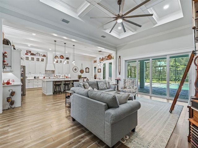 living room with ornamental molding, light hardwood / wood-style flooring, coffered ceiling, and ceiling fan