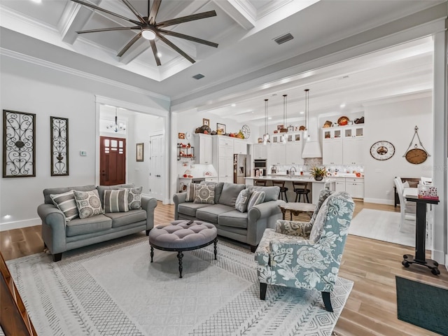 living room with ceiling fan, crown molding, light wood-type flooring, coffered ceiling, and beam ceiling