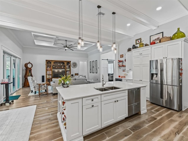 kitchen featuring ceiling fan, beamed ceiling, hardwood / wood-style floors, appliances with stainless steel finishes, and a center island with sink