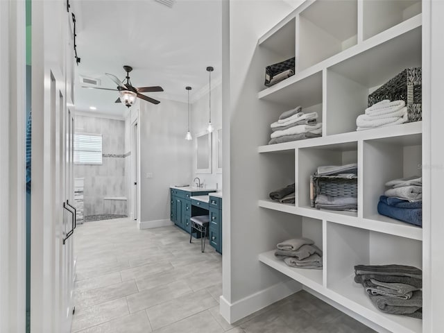 spacious closet with sink, light tile patterned floors, and ceiling fan