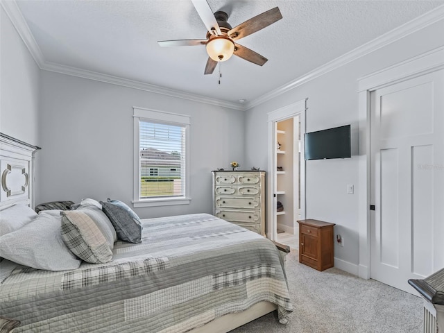 carpeted bedroom featuring ornamental molding, a spacious closet, a textured ceiling, and ceiling fan