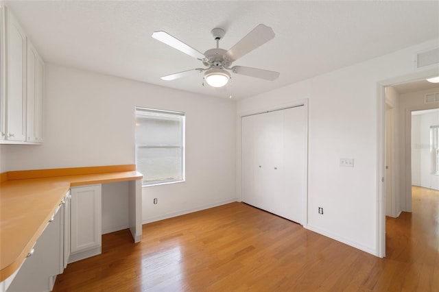 interior space featuring built in desk, light hardwood / wood-style floors, a closet, and ceiling fan