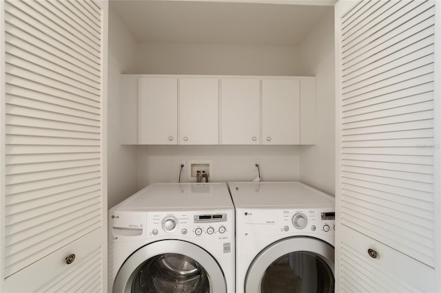 clothes washing area with cabinets and washing machine and clothes dryer