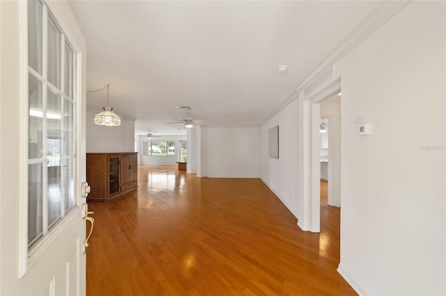 unfurnished living room with wood-type flooring, ornamental molding, and ceiling fan