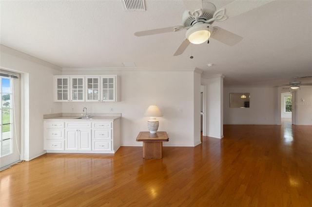 kitchen with crown molding, sink, light hardwood / wood-style flooring, and white cabinets