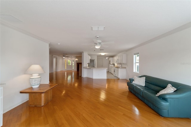 living room featuring crown molding, ceiling fan, and light hardwood / wood-style flooring