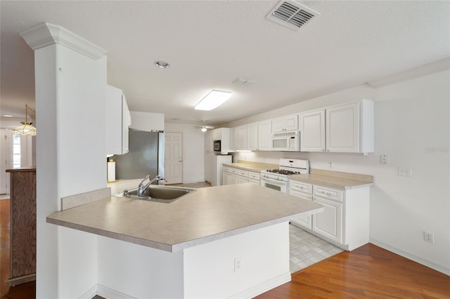 kitchen with sink, white cabinets, kitchen peninsula, white appliances, and light hardwood / wood-style flooring