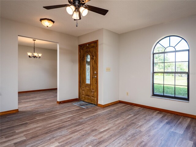 foyer with ceiling fan with notable chandelier and hardwood / wood-style floors