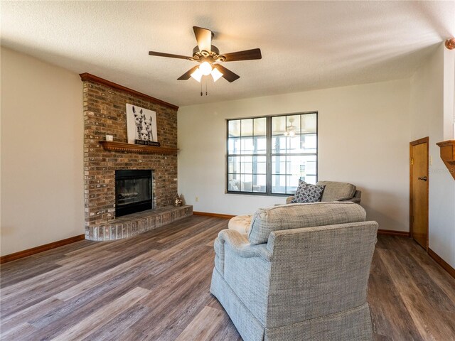 living room featuring ceiling fan, a textured ceiling, a brick fireplace, and hardwood / wood-style floors