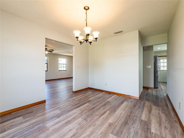 spare room with ceiling fan with notable chandelier and hardwood / wood-style flooring