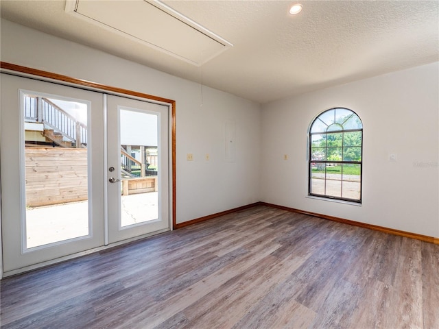 empty room featuring wood-type flooring, french doors, and a textured ceiling