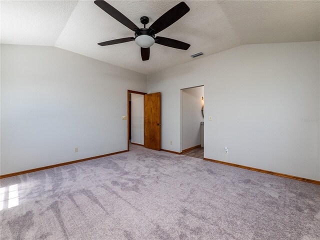 carpeted spare room featuring a textured ceiling, ceiling fan, and lofted ceiling