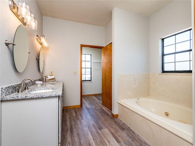 bathroom with wood-type flooring, a bathing tub, vanity, and a textured ceiling