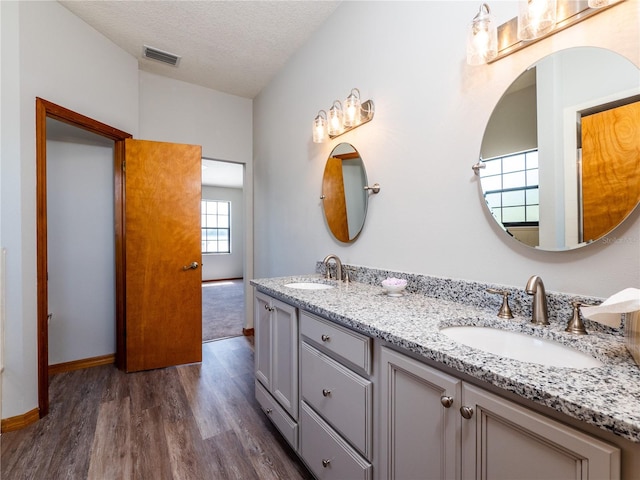 bathroom featuring a textured ceiling, hardwood / wood-style floors, and double sink vanity