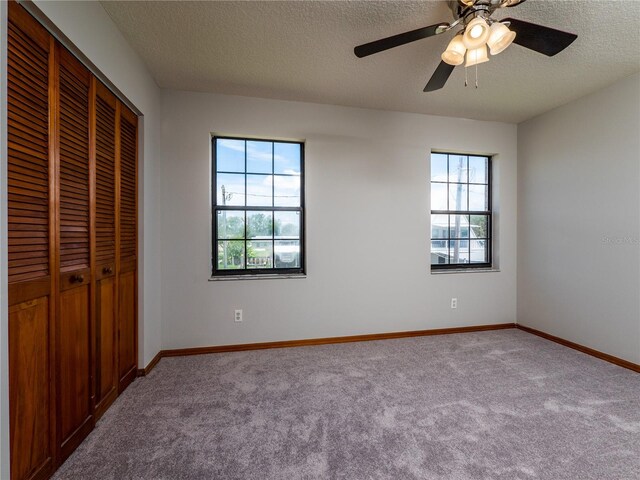 unfurnished bedroom with carpet flooring, multiple windows, and a textured ceiling