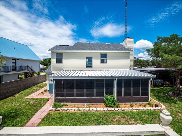 back of property with a sunroom and a yard