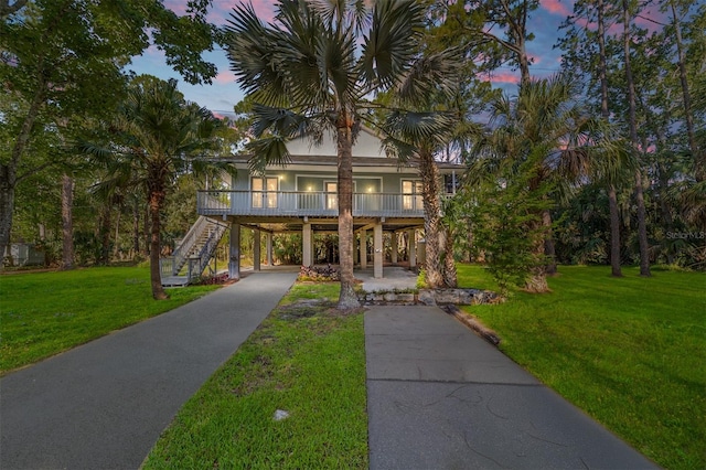 beach home featuring a carport, a porch, and a lawn