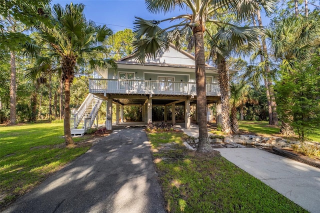 coastal inspired home with a carport, a porch, and a front yard