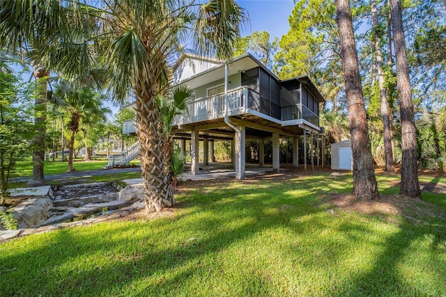 back of house featuring a lawn, a sunroom, and a storage unit