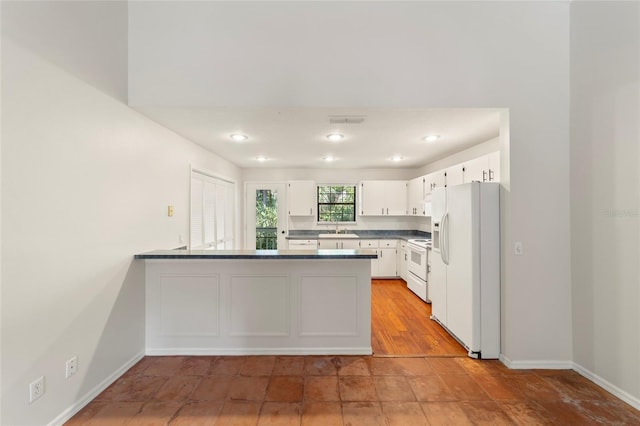 kitchen with sink, white appliances, kitchen peninsula, and white cabinets