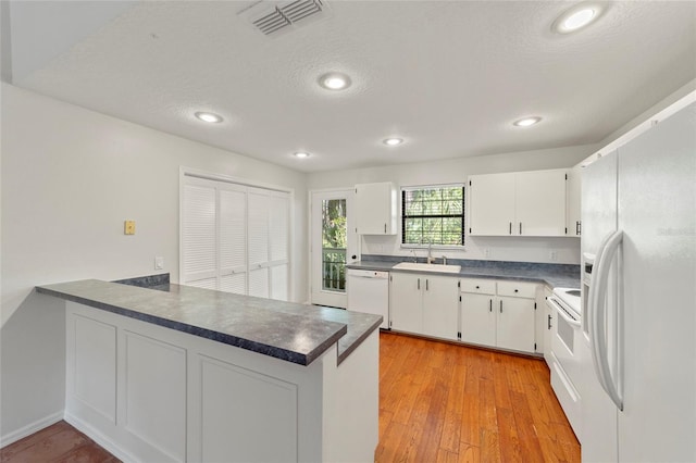 kitchen with sink, white cabinets, white appliances, and kitchen peninsula