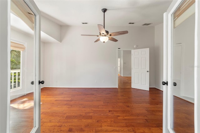 unfurnished room featuring french doors, ceiling fan, and dark wood-type flooring