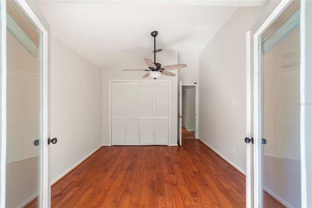 unfurnished bedroom featuring ceiling fan, lofted ceiling, dark hardwood / wood-style flooring, and a closet