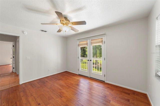 empty room featuring hardwood / wood-style flooring, ceiling fan, a textured ceiling, and french doors