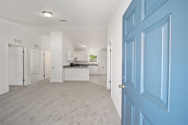 unfurnished living room with sink, lofted ceiling, and light colored carpet