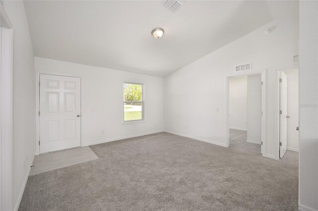 carpeted spare room with vaulted ceiling