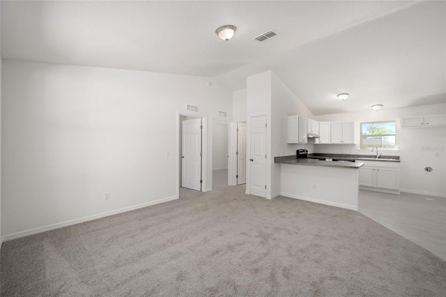 unfurnished living room with light carpet, lofted ceiling, and sink