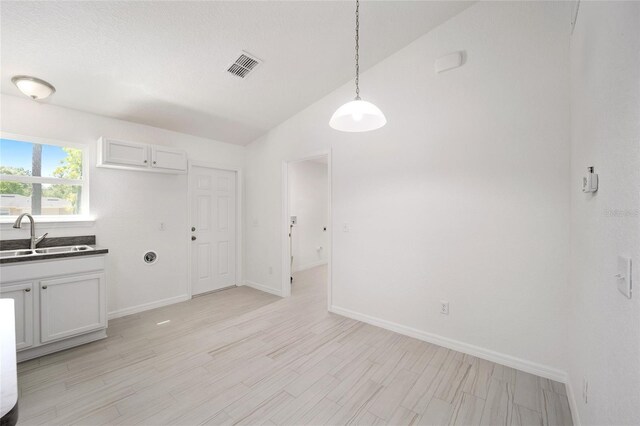 unfurnished dining area with light hardwood / wood-style floors, sink, and high vaulted ceiling