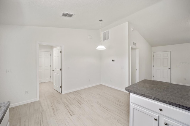 kitchen featuring light hardwood / wood-style floors, white cabinetry, lofted ceiling, and hanging light fixtures