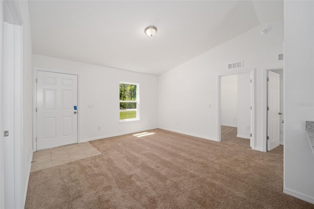 carpeted spare room featuring vaulted ceiling