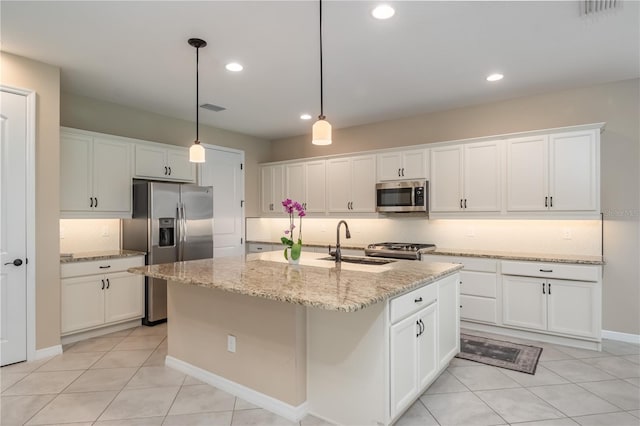 kitchen featuring sink, appliances with stainless steel finishes, light stone countertops, and an island with sink