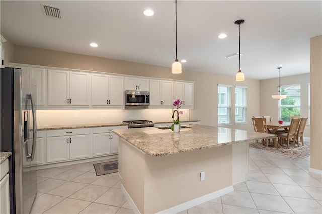 kitchen featuring light tile patterned floors, a center island, hanging light fixtures, appliances with stainless steel finishes, and sink