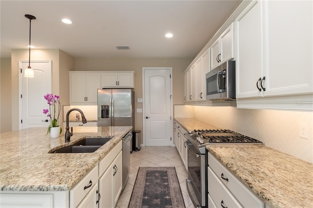 kitchen with decorative light fixtures, stainless steel appliances, a center island with sink, and light tile patterned floors