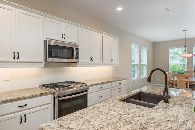 kitchen with sink, appliances with stainless steel finishes, white cabinets, and a wealth of natural light