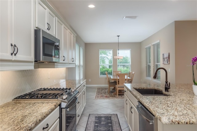 kitchen featuring stainless steel appliances, sink, hanging light fixtures, decorative backsplash, and white cabinetry