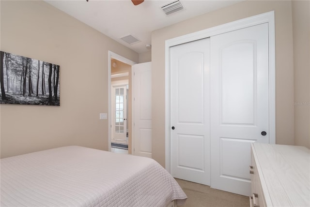 bedroom featuring light colored carpet, a closet, and ceiling fan