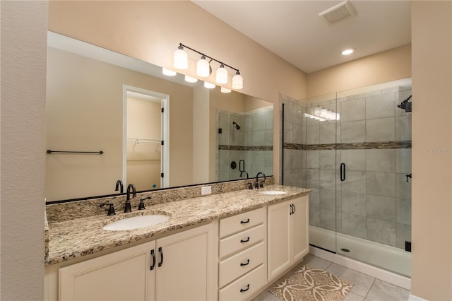 bathroom with dual vanity, an enclosed shower, and tile patterned flooring