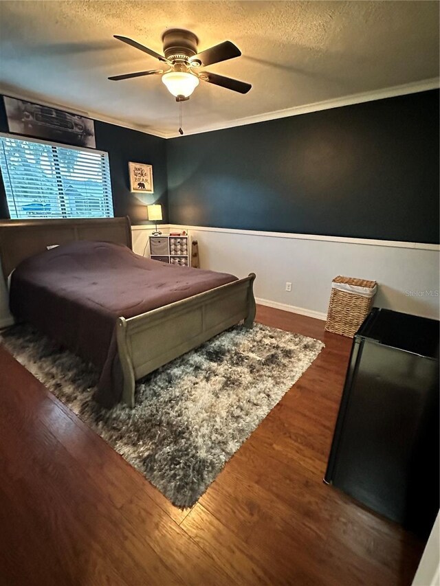 bedroom with ceiling fan, a textured ceiling, hardwood / wood-style flooring, and ornamental molding