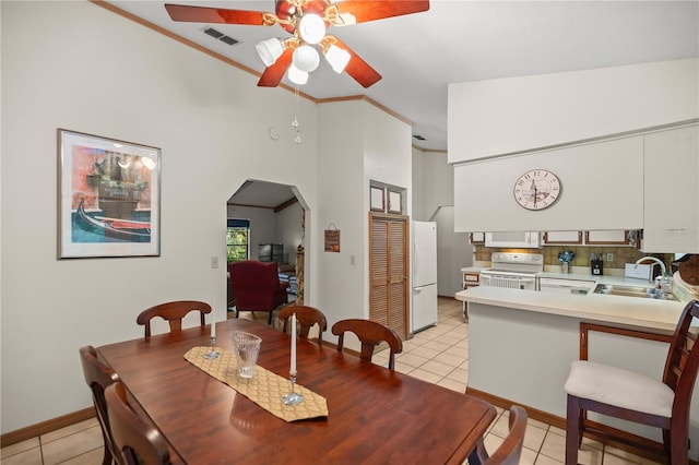 dining area with light tile patterned flooring, high vaulted ceiling, sink, and ceiling fan