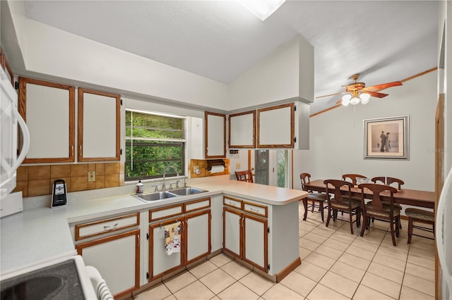 kitchen featuring lofted ceiling, tasteful backsplash, kitchen peninsula, ceiling fan, and sink