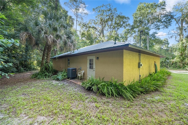 view of side of home with central AC and a yard