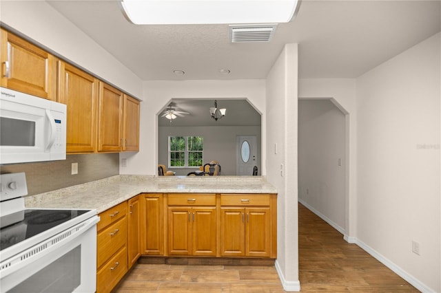 kitchen featuring ceiling fan with notable chandelier, light hardwood / wood-style floors, and white appliances