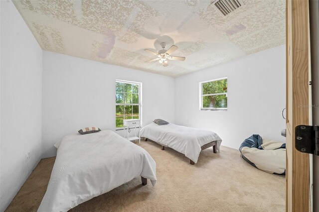 carpeted bedroom featuring a textured ceiling and ceiling fan