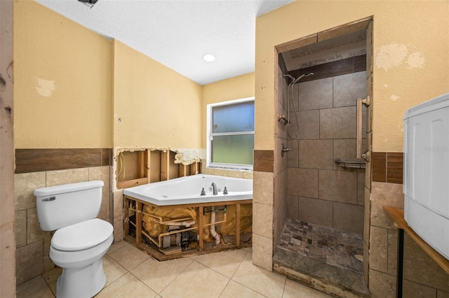 bathroom with toilet, separate shower and tub, tile patterned flooring, and tile walls