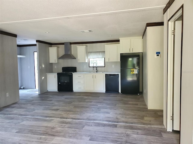 kitchen with white cabinetry, hardwood / wood-style flooring, wall chimney exhaust hood, and black appliances